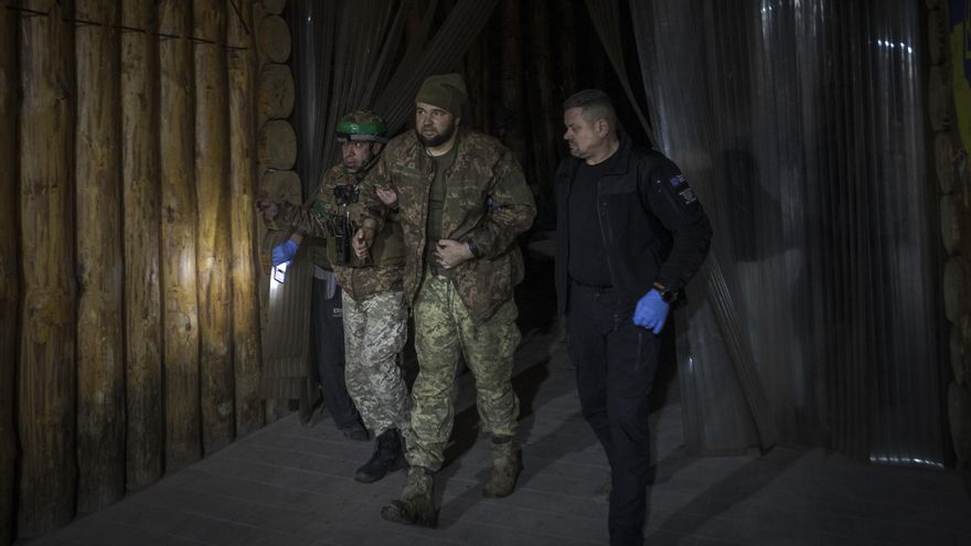 Los militares 'Doc' y Pavlo acompañan a un militar herido recién evacuado, tras sufrir un ataque ruso de artillería que impactó sobre el búnker donde se encontraba a unos dos kilómetros del frente.