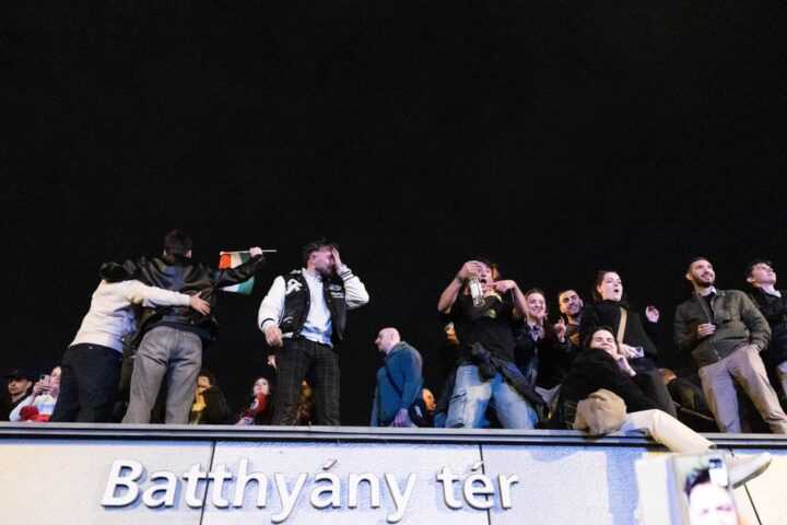Jóvenes subidos al edificio del metro celebran los resultados electorales.