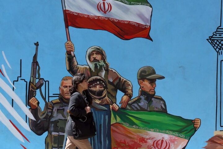 Una mujer pasa junto a un mural político en Teherán.